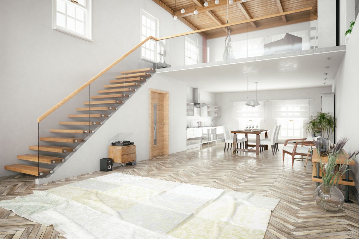 A sleek modern loft with stairs leading to a kitchen, highlighting premium flooring service throughout the space.