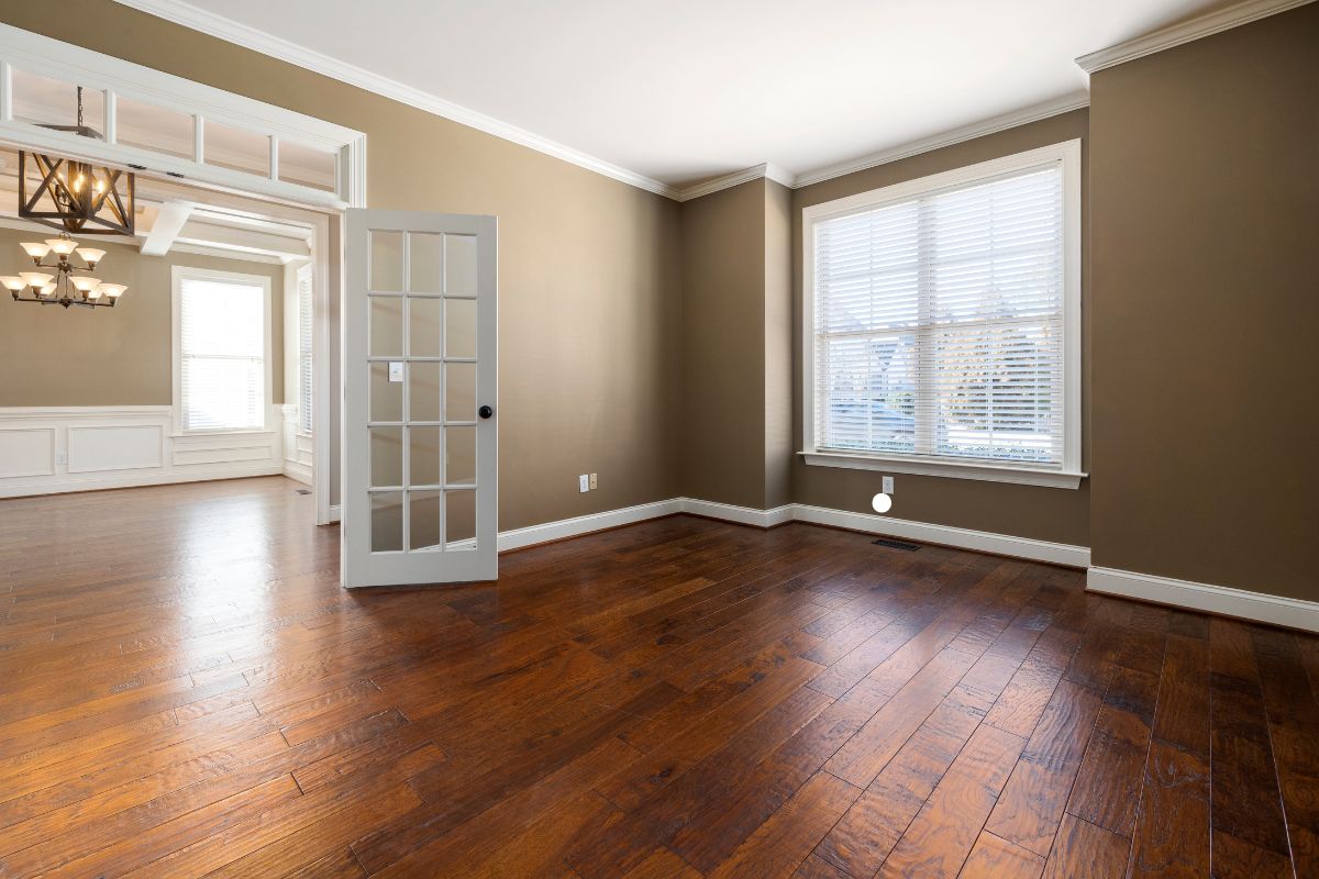 A well-lit room featuring polished hardwood floors and a door, showcasing quality flooring service.