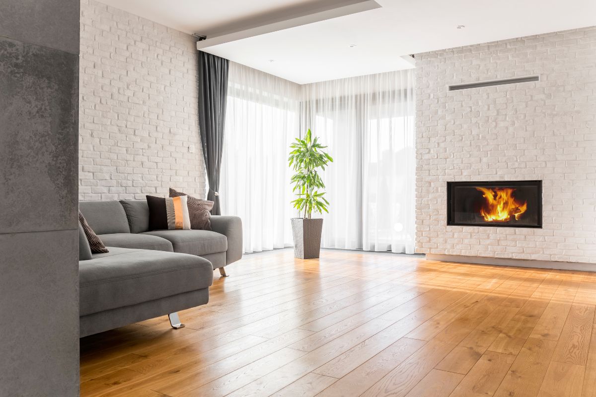A cozy living room featuring a fireplace and a comfortable couch, showcasing elegant top flooring service.