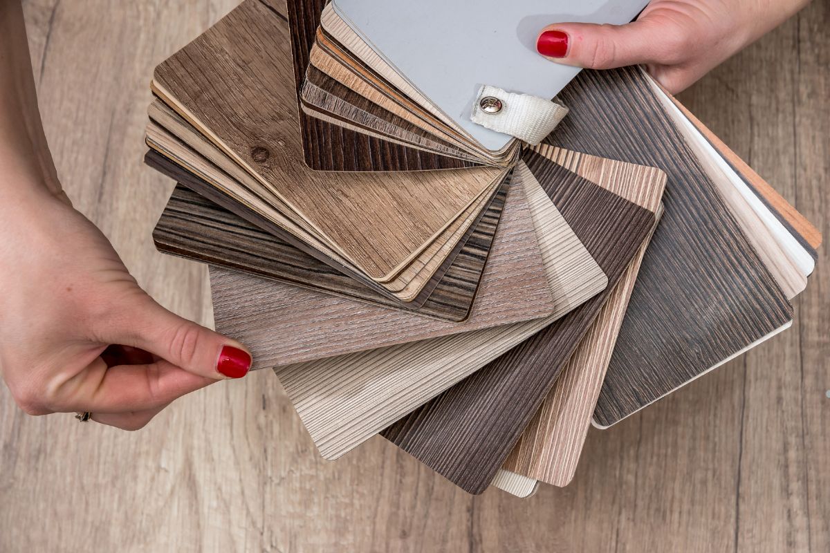 A woman presents a variety of wood flooring samples, including vinyl options, showcasing flooring services available.